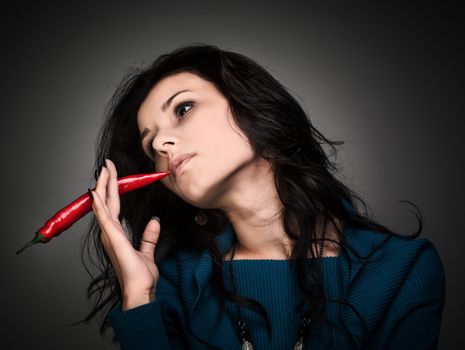 young lady holding red hot chilli pepper in mouth