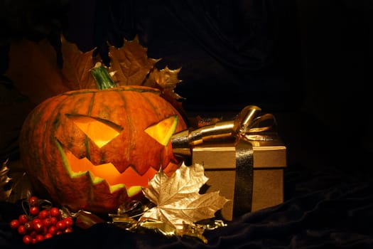 Halloween pumpkin with autumn leafs and gift on black