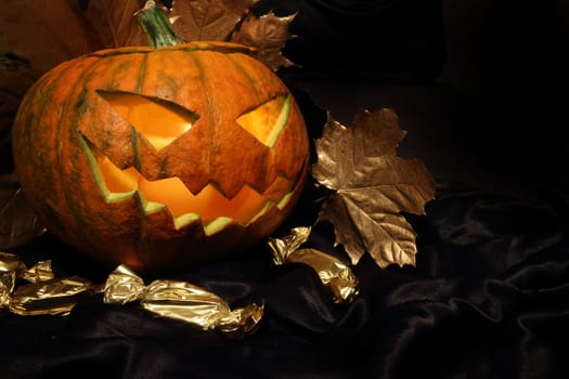 Halloween pumpkin with autumn leafs on black