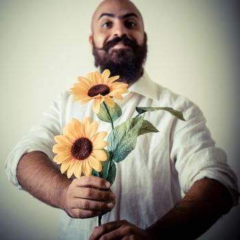 long beard and mustache man giving flowers on gray background