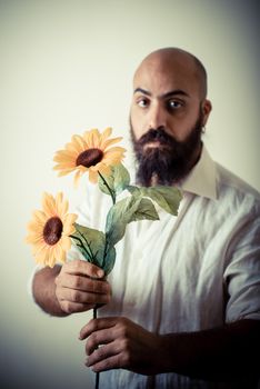 long beard and mustache man giving flowers on gray background