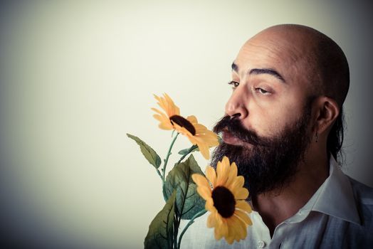 long beard and mustache man giving flowers on gray background