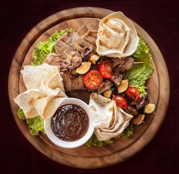 Meat and vegetable delicacies served on a wooden tray