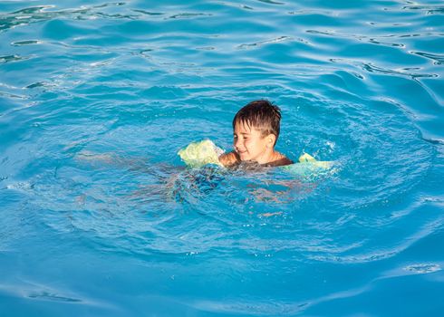 Little boy learning to swim in the pool 