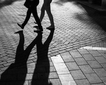 Shadows of people walking street in morning light