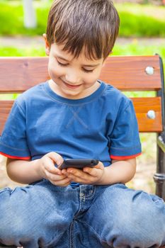 Happy little boy smiling and playing with smartphone