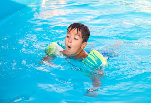 Little boy learning to swim in the pool 