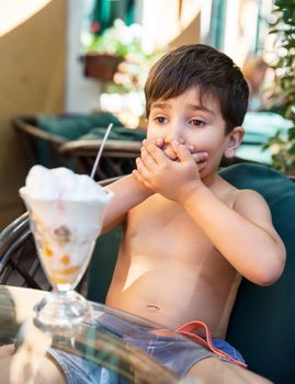 Llittle boy closes the mouth with his hands refusing to eat ice cream