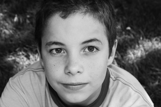 Cute boy smiling at camera in the park on a sunny day