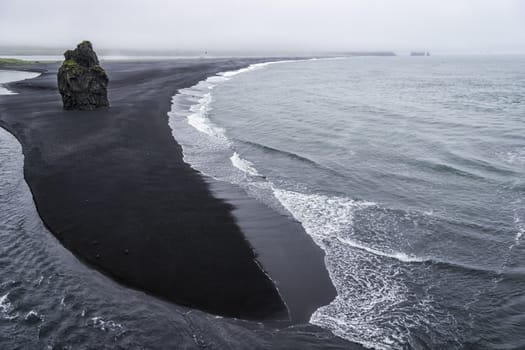 Black volcanic sand on the south coast of Iceland in rainy weather