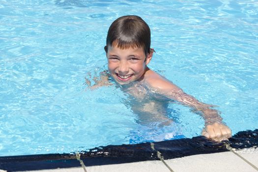 Activities on the pool. Cute boy swimming and playing in water in swimming pool