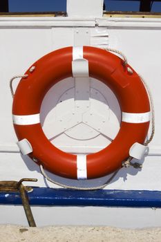 Orange ring buoy hanging on white painted boat