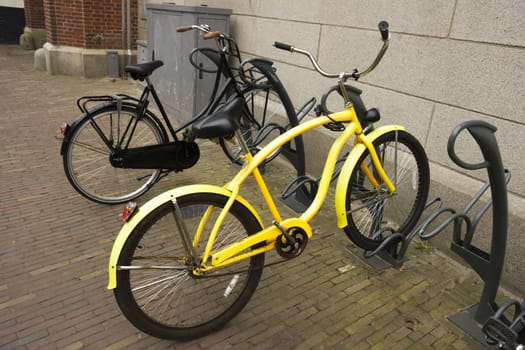 yellow bike with flat tyre parked in a bicycle parking