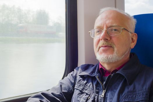 Relaxed old man sitting near the window in the carriage