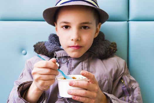 Cute teenage boy eating ice cream with chocolate topping