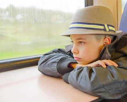 Boy rides on a train and looking out the window.