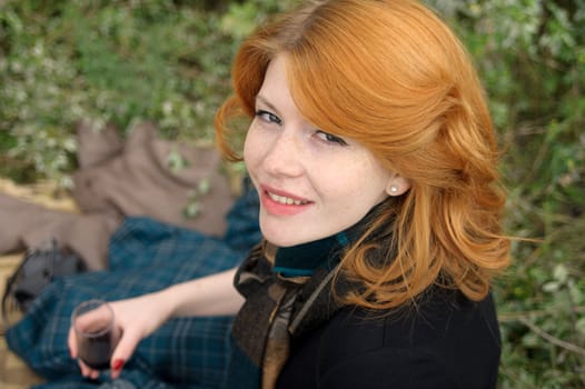 Portrait of a beautiful redhair girl in the autumn park. Caucasian race.