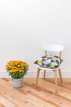 Bright cushion on a chair, and orange chrysanthemums decorating a room.