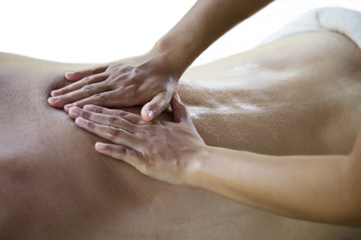 Therapist  giving a back massage at a young male in a spa