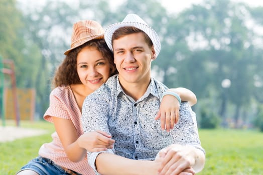 romantic couple lying on the grass in the summer park, spending time with loved ones