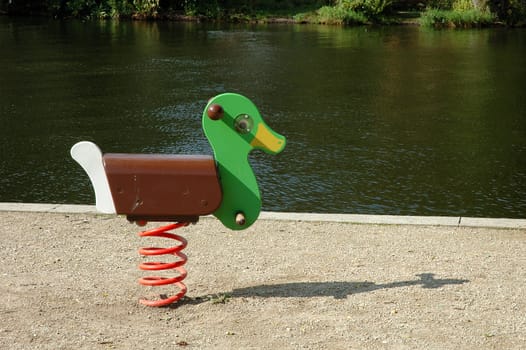 Duck swing on playground on river bank
