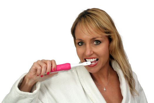 A lovely blonde brushes her teeth with an electric toothbrush.  Isolated on a white background.