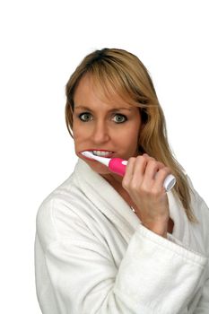 A lovely blonde brushes her teeth with an electric toothbrush.  Isolated on a white background.