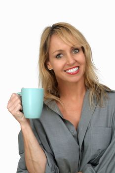 A lovely blonde with a captivating smile and wearing a man's button-down shirt, enjoys a hot beverage.  Isolated on a white background.