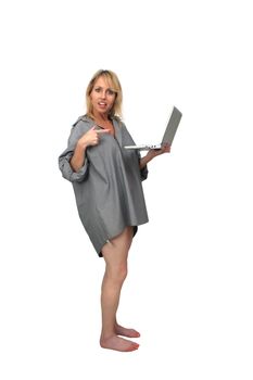 A lovely blonde wearing only a man's button-down shirt, points to the laptop computer in her hand.  Isolated on a white background.