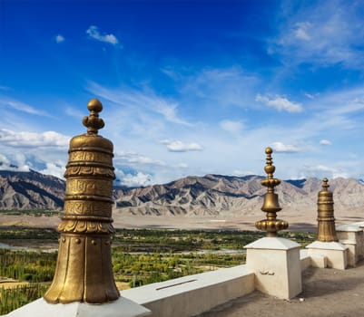 Dhvaja (victory banners), on the roof of Thiksey gompa (Tibetan BUddhistm monastery) and view of Indus valley. Ladakh, India