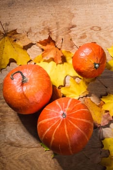 Autumn background with colored leaves and pumpkin on wooden board. Pumpkins on grunge wooden backdrop, background table. Autumn, halloween, pumpkin