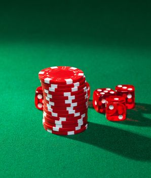 Red poker chips and red dice on green cloth