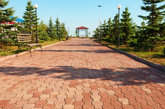 Wide path in nice light  park with benches and summerhouse under clean blue sky