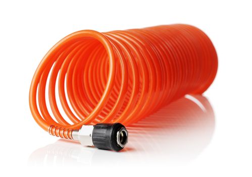 Orange red thin spiral air hose used for pneumatic tools. Isolated on white with natural reflection. Very short depth-of field, the sharpness is in the connector.