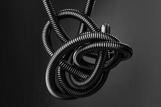 Black and white image of a black tangled flexible hose.