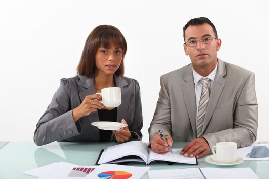 businessman and businesswoman examining a project and drinking coffee