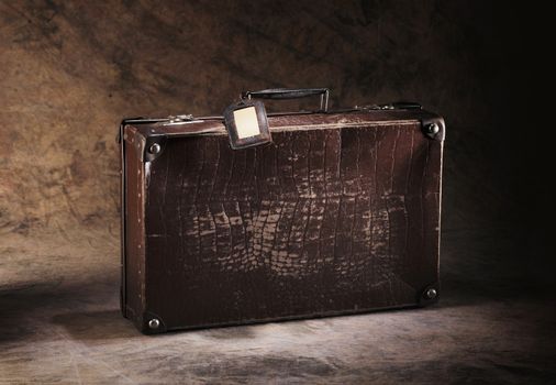 Old brown cardboard suitcase on brown rustic background.