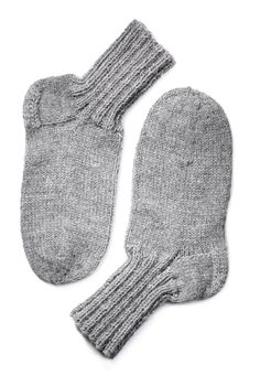 A Pair of hand-knit grey wool socks on white background with natural shadows. 