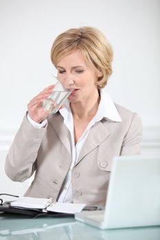 Businesswoman drinking a glass of water at her desk