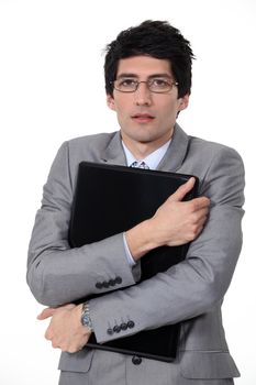 A businessman hugging his briefcase.