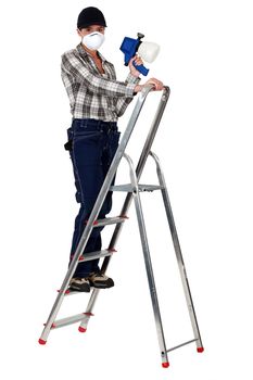 craftswoman on a ladder holding a sprayer and wearing a mask