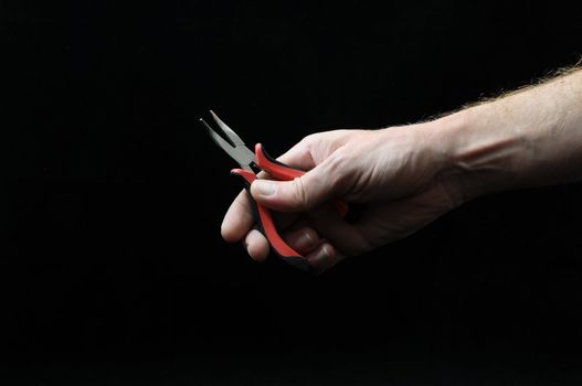 Pliers and a Hand on a Black Background