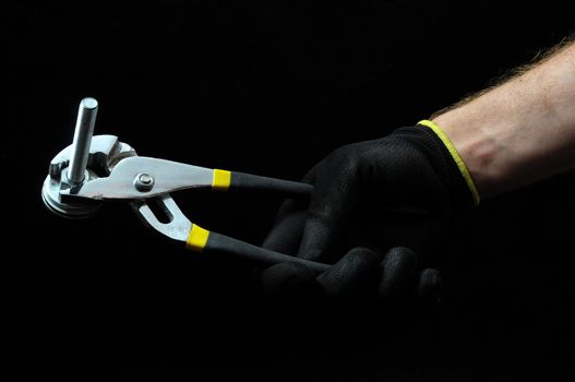 Pliers and a Hand on a Black Background