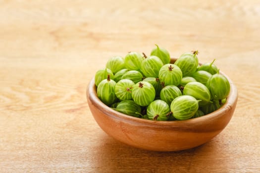 Old Wooden Bowl Filled With Succulent Juicy Fresh Ripe Green Gooseberries On An Old Wooden Table Top.