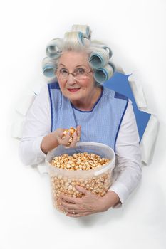 senior woman with curlers in her hair eating popcorn