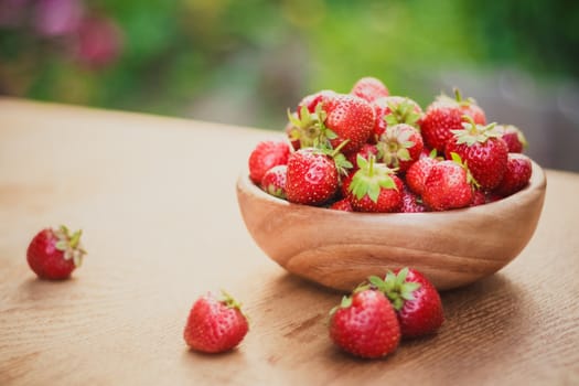 Old Wooden Bowl Filled With Succulent Juicy Fresh Ripe Red Strawberries On An Old Table top