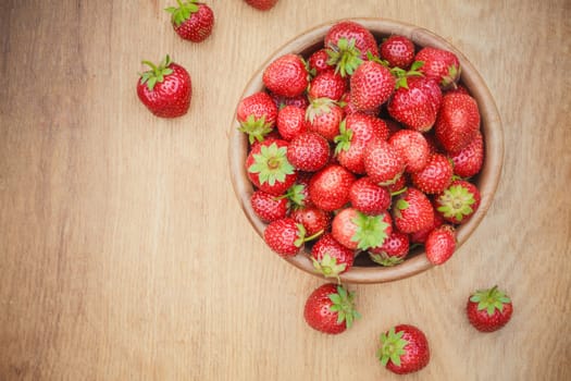 Old Wooden Bowl Filled With Succulent Juicy Fresh Ripe Red Strawberries On An Old Table top