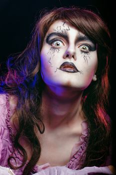 Girl in the image of a witch with a theatrical make-up in studio shot