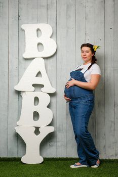 Beautiful pregnant girl on a large stage of pregnancy photographed in the studio