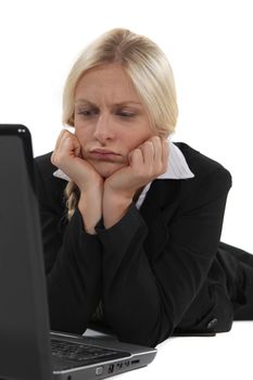 Confused blond office worker using laptop